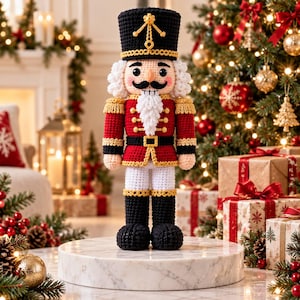 Puede incluir: Una muñeca cascanueces tejida a ganchillo con un sombrero negro alto con ribete dorado, una chaqueta roja con botones dorados, pantalones blancos y botas negras. La figura tiene barba blanca, bigote negro y piel clara, de pie.