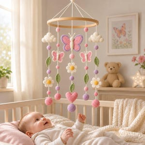 Peut inclure: Un mobile de chambre d'enfant suspendu composé d'éléments crochetés fixés à un cadre circulaire en bois. Le design comprend un papillon central rose et violet, des nuages blancs, des papillons roses plus petits, des fleurs blanches à cœur jaune, des feuilles vertes et un cœur rose, le tout agrémenté de petites sphères violettes et roses.