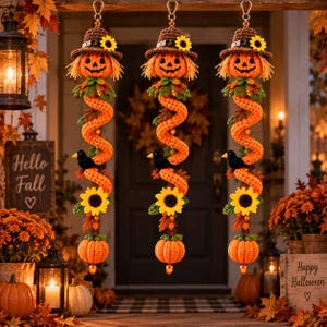 May include: Three identical hanging decorations featuring a crocheted jack-o'-lantern wearing a brown hat with a sunflower, a long orange spiral body, a black bird, a yellow sunflower, and a small orange pumpkin at the bottom.