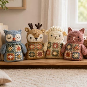 May include: Four handmade crochet stuffed animals arranged in a row. From left to right, a blue owl, a tan deer with antlers, a cream-coloured sheep, and a pink cat. Each animal features a body constructed from colourful granny square patches.