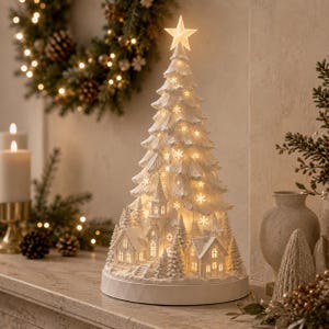 May include: A white, conical, illuminated Christmas tree sculpture featuring a star topper, snowflake cutouts, and a miniature village scene at the base. The structure is set on a circular white pedestal and emits a warm, soft glow from within.