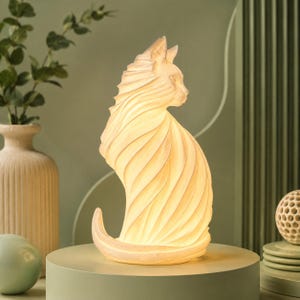 May include: A cat-shaped lamp featuring a stylized, swirling design that creates a textured, layered appearance. The lamp emits a warm, soft glow from within, highlighting the intricate curves and pointed ears of the feline silhouette.
