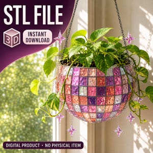 May include: A hanging planter shaped like a disco ball with a mosaic of pink, purple, and silver reflective square tiles. The planter contains a green pothos plant and features small, dangling pink star-shaped charms on silver chains.