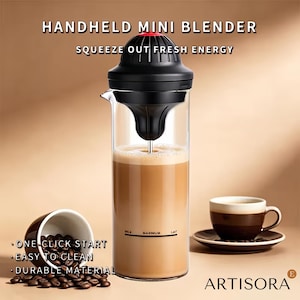 May include: A handheld mini blender with a black lid and motor unit atop a clear glass carafe containing a light brown liquid. The glass features a milk maximum fill line. Text reads HANDHELD MINI BLENDER, SQUEEZE OUT FRESH ENERGY, ONE CLICK START, EASY TO CLEAN, DURABLE MATERIAL, and ARTISORA.