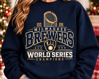 Puede incluir: Una sudadera azul marino de cuello redondo con un estampado gráfico dorado que dice 2026 Milwaukee Brewers World Series Champions, incluyendo una ilustración del trofeo y un logotipo de guante de béisbol con una pelota.