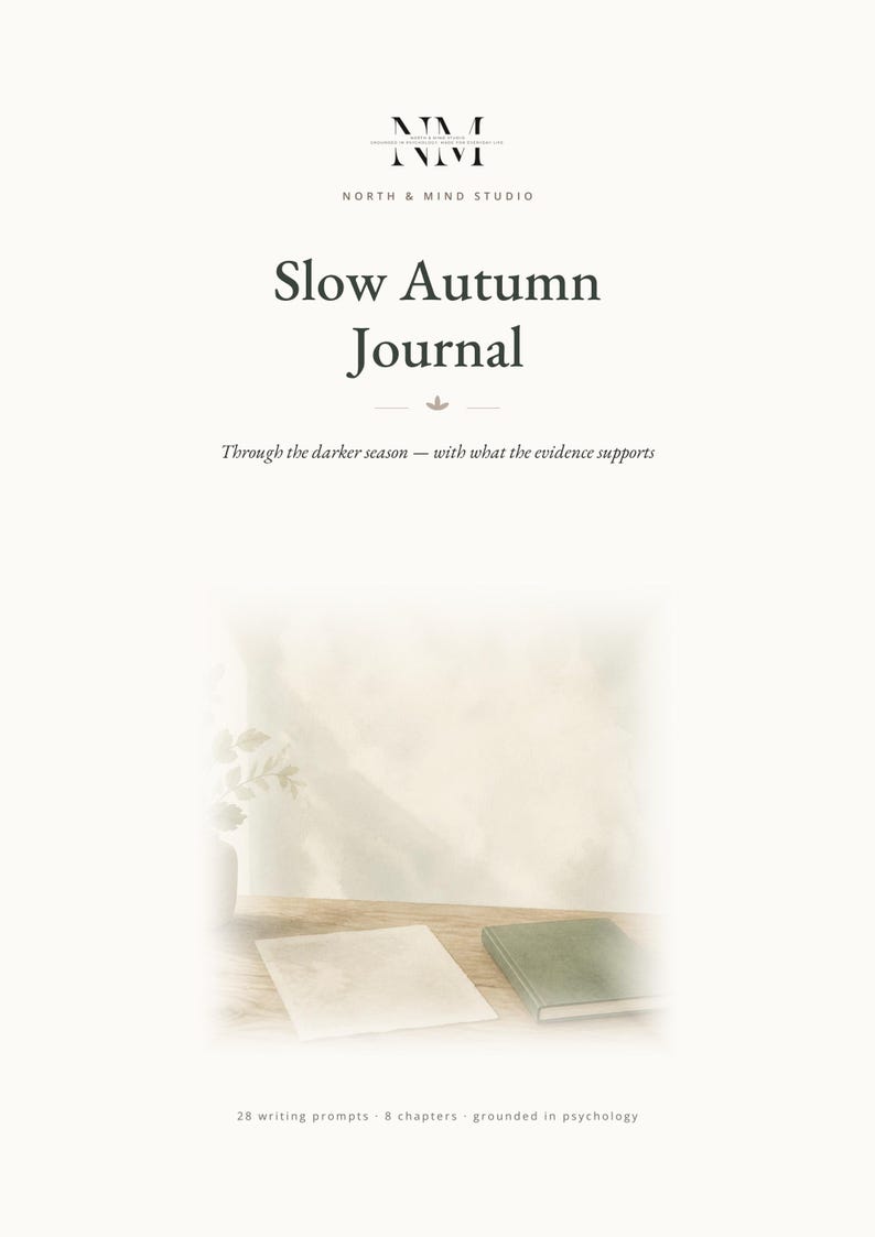 May include: A white journal cover titled Slow Autumn Journal by North & Mind Studio. The text reads: Through the darker season &mdash; with what the evidence supports. Below, a small green book and a white paper rest on a wooden surface with 28 writing prompts - 8 chapters - grounded in psychology.