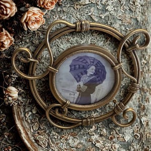 May include: A circular antique brass picture frame with ornate wire scrollwork detailing. The frame holds a black and white photograph of a person holding a striped umbrella, with the text 3x3 printed on the lower left side of the image area.