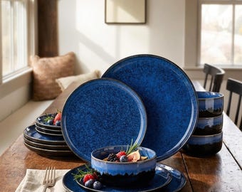 May include: A set of dark blue ceramic dinnerware featuring a mottled, speckled finish. The collection includes large dinner plates, smaller salad plates, and deep bowls with a smooth, glossy glaze and a dark, solid-colored base rim.