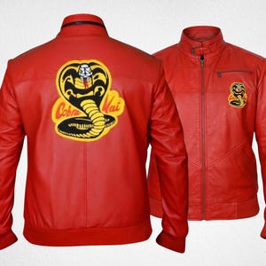 May include: A bright red jacket featuring a large Cobra Kai logo on the back and a smaller matching logo on the left chest. The jacket has a stand-up collar, a full-length front zipper, long sleeves with ribbed cuffs, and a ribbed hemline.