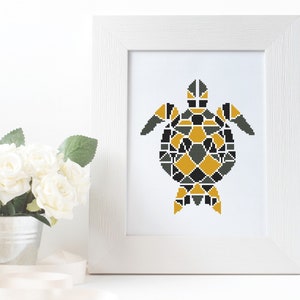 May include: A framed cross-stitch pattern of a geometric turtle in black, gray, and yellow.