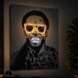 Peut inclure: Une œuvre d'art murale carrée présentant un portrait en noir et blanc à fort contraste d'une personne avec des dreadlocks. L'œuvre intègre des lunettes lumineuses de style néon jaune et des dents blanches éclatantes, créant un effet lumineux.