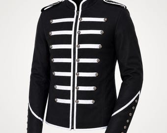 May include: A black military-style jacket featuring a high collar with white trim, a central zipper closure, and horizontal white bands across the front. The jacket includes silver-toned buttons, shoulder epaulets, and white piping on the cuffs.