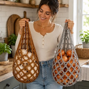May include: Two reusable crochet produce bags with a diamond mesh pattern. One bag is a warm brown color filled with white garlic bulbs, and the other is a cool gray color filled with yellow onions. Both bags feature sturdy handles for carrying.