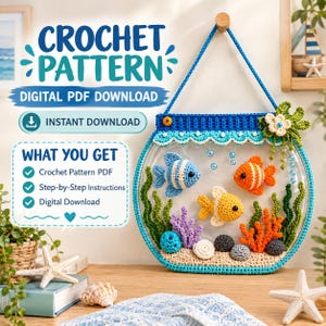 May include: A crochet pattern digital PDF download featuring a wall-hanging fishbowl display. The circular blue frame contains three crocheted fish in blue, orange, and yellow, surrounded by crocheted seaweed, coral, and pebbles on a sandy base.