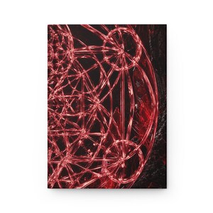 May include: A rectangular notebook featuring a vibrant red geometric pattern on a black background. The design consists of intricate intersecting circles and lines that create a complex, glowing structure across the front cover surface.