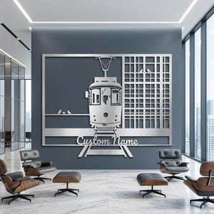 May include: A rectangular silver-toned metal wall art piece featuring a central tram design, a grid pattern on the right, and small bird silhouettes on a wire. The text Custom Name is cut out in a script font above the tram tracks.