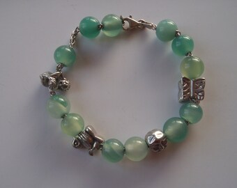 May include: A green jade bracelet with silver charms, including a butterfly, a bird, and a flower.