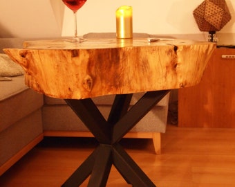 May include: A wooden table with a natural wood top and black metal legs. The table has a unique, irregular shape and is perfect for a living room or bedroom. A glass of red wine and a candle are on the table.