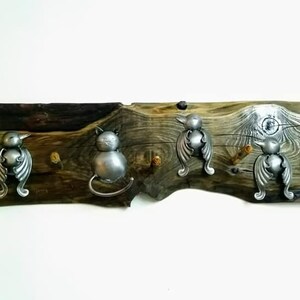 May include: A wooden wall-mounted coat rack with five hooks. The hooks are shaped like stylized birds and cats. The wood is a dark brown with a natural grain pattern.