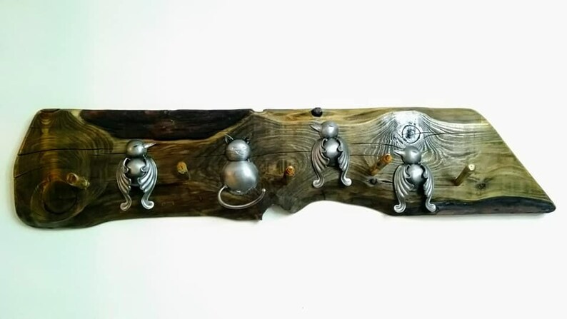May include: A wooden wall-mounted coat rack with five hooks. The hooks are shaped like stylized birds and cats. The wood is a dark brown with a natural grain pattern.