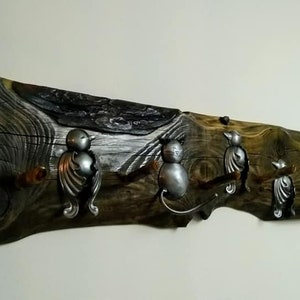 May include: A rustic wooden coat rack with three metal bird hooks. The wood is dark brown with a natural grain pattern. The hooks are silver and have a detailed bird design.