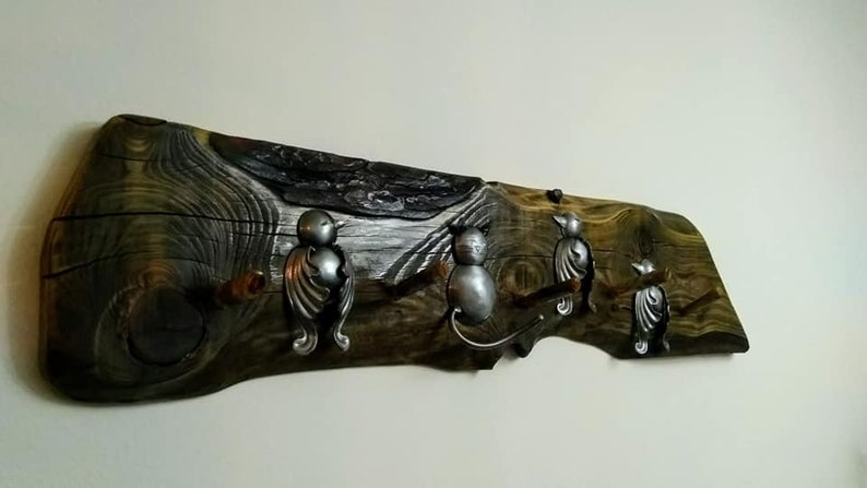 May include: A rustic wooden coat rack with three metal bird hooks. The wood is dark brown with a natural grain pattern. The hooks are silver and have a detailed bird design.