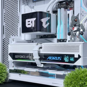 Puede incluir: Un interior de caja de ordenador blanco con un bloque de refrigeración líquida con el logotipo de Aorus, una tarjeta gráfica Aorus GeForce RTX blanca con pantalla digital que muestra 48 grados Celsius y una pequeña figura robótica gris.