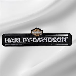 May include: A rectangular black embroidered patch featuring the white text HARLEY-DAVIDSON centered between two horizontal white lines. Above the text is a small black shield emblem with orange and white Harley-Davidson Motor Cycles lettering.