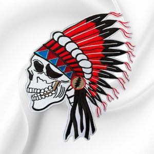 May include: An embroidered patch featuring a white skull wearing a large headdress with red and black feathers, a white band with blue and red triangles, and a circular emblem with a lightning bolt symbol on the side of the head.