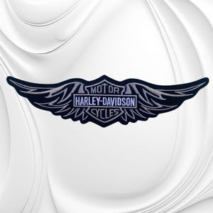 May include: A black embroidered patch featuring a central shield shape with the text MOTOR HARLEY-DAVIDSON CYCLES in white lettering. The shield is flanked by stylized, pointed black and white wings that extend horizontally from the center.