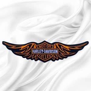 May include: A black embroidered patch featuring the Harley-Davidson Motor Cycles logo in orange and white thread. The design includes stylized wings extending from a central shield shape with the text MOTOR HARLEY-DAVIDSON CYCLES.