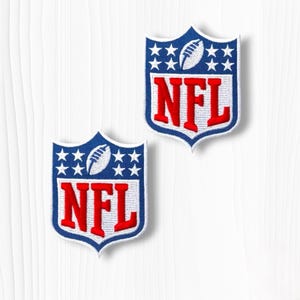 May include: Two embroidered patches featuring the NFL logo in a shield shape. Each patch has a blue upper section with white stars and a white football icon, and a white lower section with the red letters NFL outlined in blue and white.