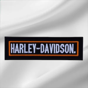 May include: A rectangular embroidered patch featuring a black background with a bold orange border. The text HARLEY-DAVIDSON is stitched in white capital letters across the center of the patch, creating a clear and high-contrast design.