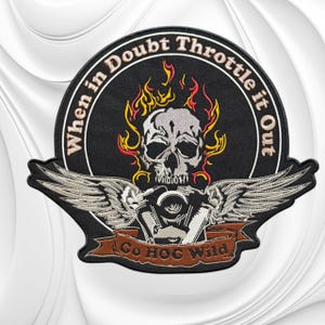 May include: A circular embroidered patch featuring a central grey skull surrounded by yellow and red flames. Below the skull are silver wings and a brown banner with the text "Go HOG Wild". The border text reads "When in Doubt Throttle it Out".