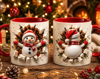 May include: Two white ceramic mugs with red interiors and handles, featuring a 3D-effect design of a snowman wearing a red hat and scarf, appearing to emerge from a cracked wall surrounded by festive greenery and small red berries.