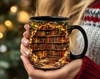 May include: A black ceramic mug featuring a printed graphic of a cozy, arched stone library interior filled with rows of colorful books, warm glowing lanterns, hanging greenery, and an open book resting on a stone floor with scattered candles.