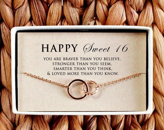 May include: A white gift box containing a gold chain necklace. The box features a card with the message "HAPPY Sweet 16 YOU ARE BRAVER THAN YOU BELIEVE, STRONGER THAN YOU SEEM. SMARTER THAN YOU THINK. & LOVED MORE THAN YOU KNOW."