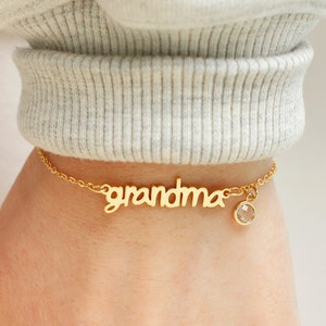 May include: Gold chain bracelet with a charm that says "grandma" and a clear crystal charm.