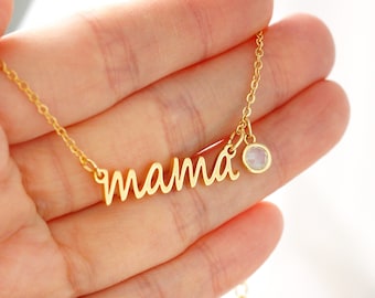 Pode incluir: Colar de ouro com um pingente de "mama" em escrita cursiva e um pequeno charme de pedra preciosa iridescente.