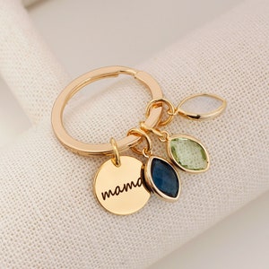 A gold O shaped keychain with coins and boat shaped birthstone Personalized text, mama engraved on the coin. Customers can personalize birthstones and engraving 
for their mother. The most common comments are cute, pretty and high quality!