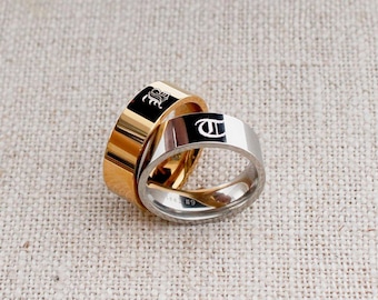 May include: Two gold and silver rings with engraved initials. The gold ring has a "B" engraved on it and the silver ring has a "T" engraved on it.