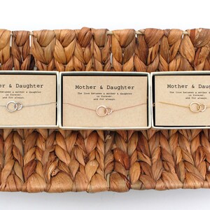 May include: Three gift boxes with the text "Mother & Daughter" and the phrase "The love between a mother & daughter is forever and for always." Each box contains a delicate necklace with two interlocking circles.