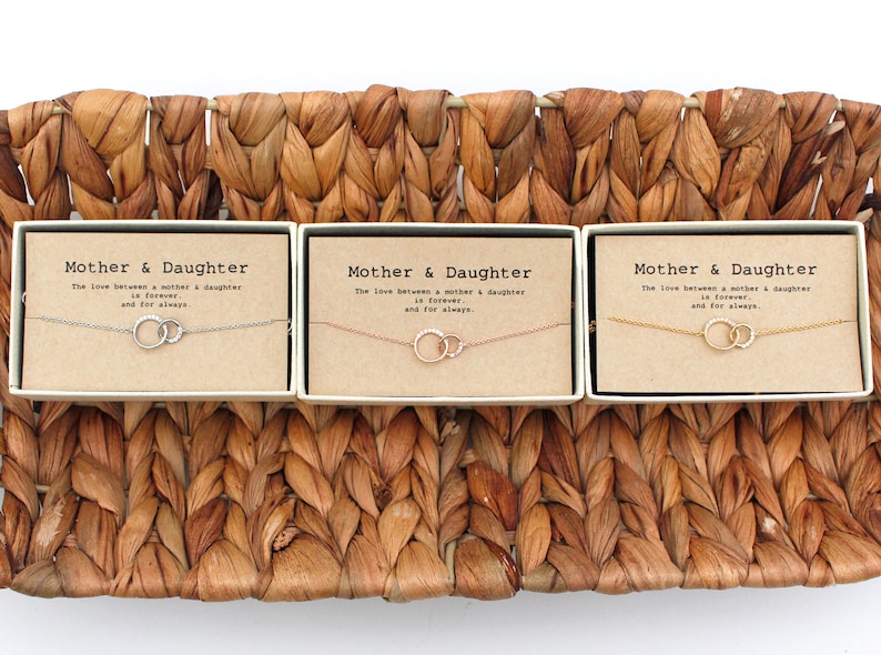 May include: Three gift boxes with the text "Mother & Daughter" and the phrase "The love between a mother & daughter is forever and for always." Each box contains a delicate necklace with two interlocking circles.