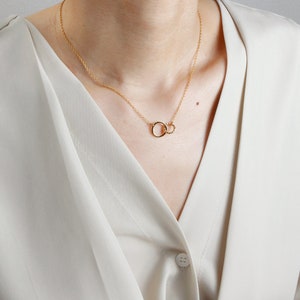 May include: A gold necklace with two interlocking circles as a pendant.