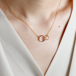 Puede incluir: Un collar de oro con dos c&iacute;rculos entrelazados. El c&iacute;rculo m&aacute;s peque&ntilde;o est&aacute; retorcido.