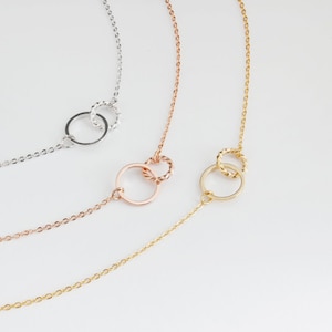 May include: Three delicate necklaces with interlocking circle pendants. The necklaces are silver, gold, and rose gold.