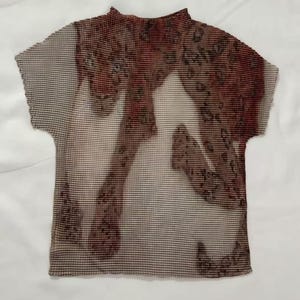 May include: A short-sleeved, pleated top featuring a high neckline and a brown and beige leopard print pattern. The garment has a textured, accordion-like finish throughout the fabric, with a repeating animal spot design across the front surface.