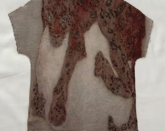 May include: A short-sleeved, pleated top featuring a high neckline and a brown and beige leopard print pattern. The garment has a textured, accordion-like finish throughout the fabric, with a repeating animal spot design across the front surface.