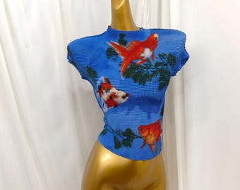 May include: A bright blue short-sleeved top with a textured, pleated fabric surface. The garment features a repeating graphic print of orange and white goldfish swimming among dark green aquatic plants across the entire front and side panels.