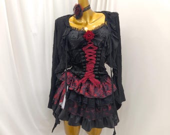 May include: A black long-sleeved top featuring a red lace-up corset front, a red rose accent, and a layered skirt with black and red patterned fabric. The garment includes a matching black choker with a dark red rose detail.